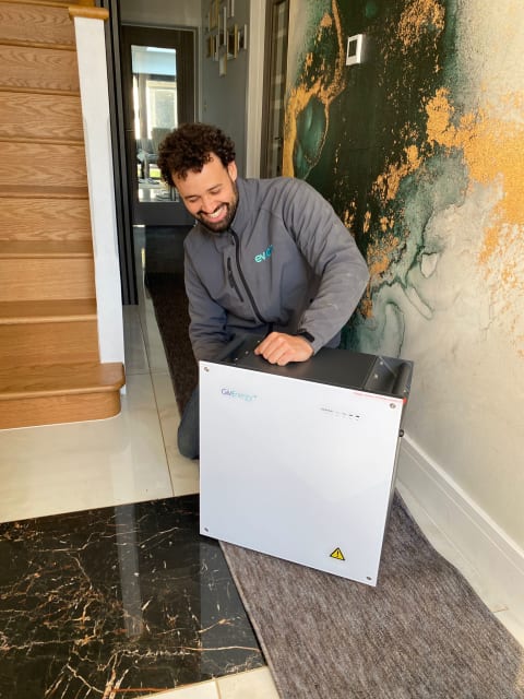 An evon engineer installing a GivEnergy home battery storage unit in the hallway of a domestic property in the UK.