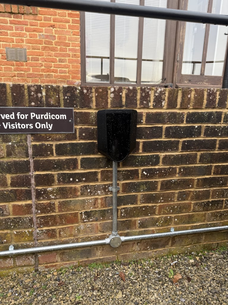 Easee charger above a reserved visitor parking sign with galvanised conduit drop at Purdicom, Wantage.