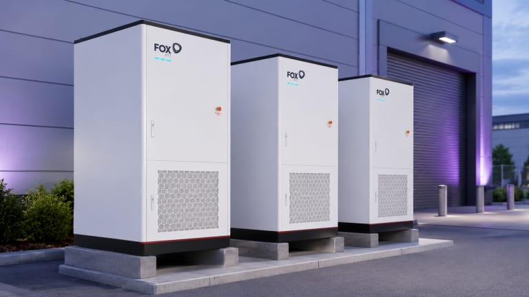 Three Fox ESS G-Max commercial battery storage cabinets outside an industrial unit at dusk.