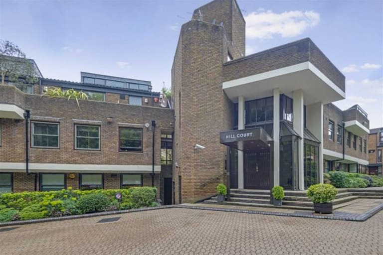 The main entrance of Hill Court residential apartments showing the building name sign and landscaped forecourt in Highgate, London
