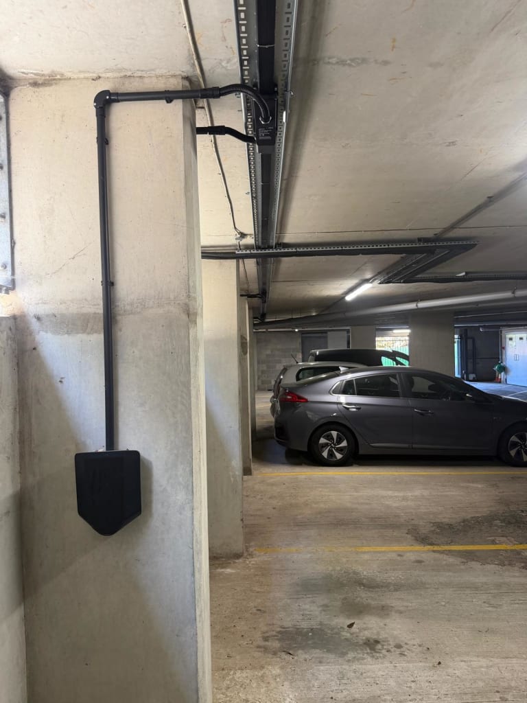 Easee Home EV charger wall-mounted on a concrete column next to a Hyundai in an EV charging bay at Portland Court, Hendon, London.