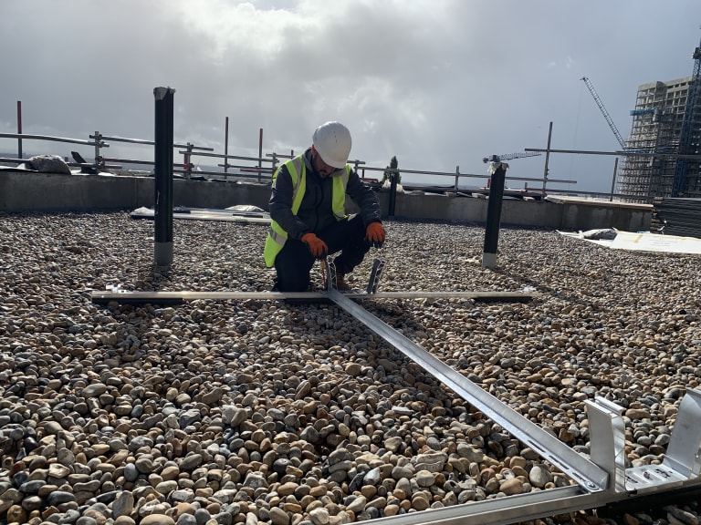 EV-ON engineer installing K2 D-Dome Xpress solar mounting rail on the Level 6 flat roof at The Mirador, Acton.