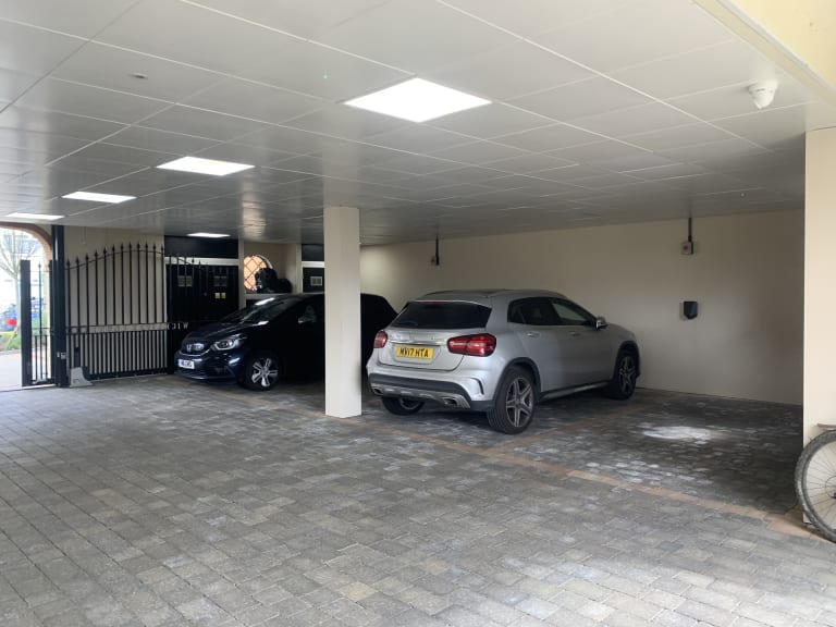 Interior view of a covered car park with block paved surface and vehicles parked at a residential complex in Hendon