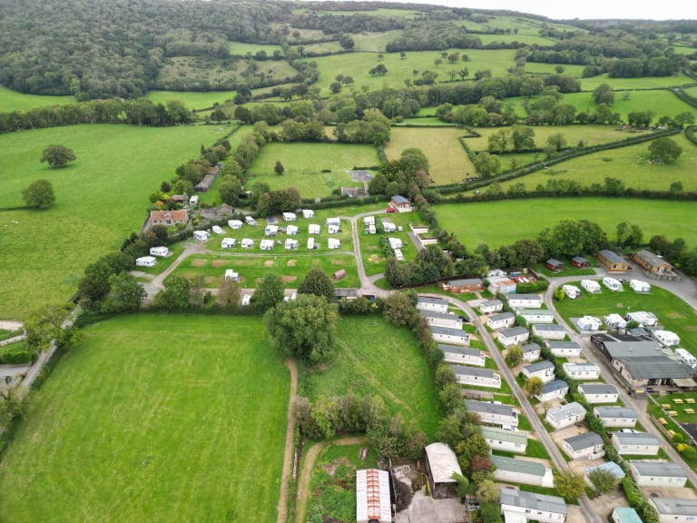 Aerial view of a UK caravan holiday park with touring and static caravans set among green countryside fields.