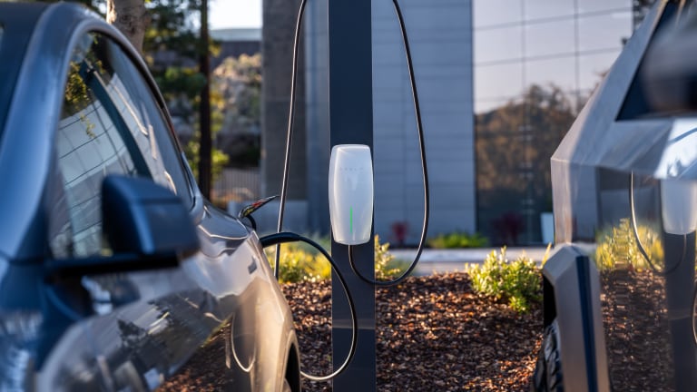 Close up of a Tesla Destination Charging connector cable plugged into a car outside an office building.