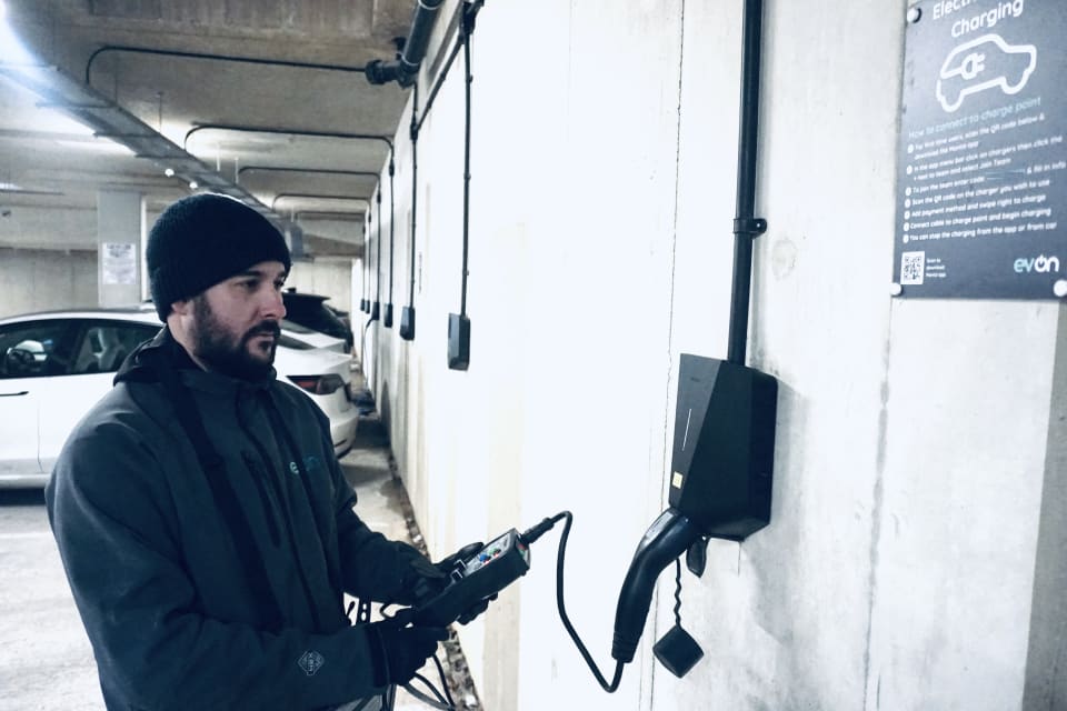 An evon engineer running maintenance tests on a wall mounted Easee EV charger in the underground car park at Millbrook Park