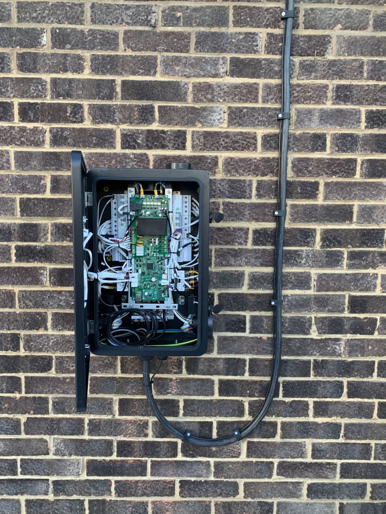 An EV charger enclosure opened to show the internal board and breakers during fault diagnosis