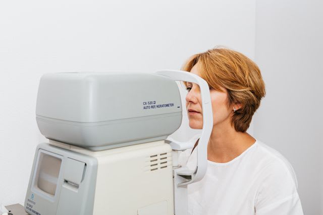 Photo d’une femme réalisant un examen de la vue à l’aide d’un autoréfractomètre chez un professionnel de santé.