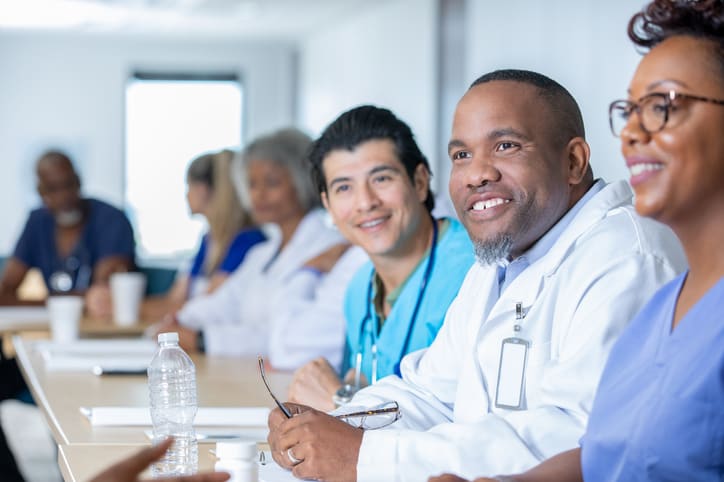 Healthcare professionals smiling and consulting with each other in a clinical setting.