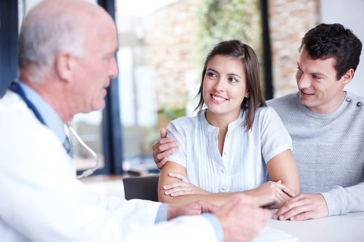 Un médecin expliquant un diagnostic à un couple de patients souriants