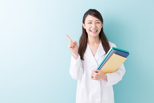 Une médecin souriante avec des dossiers médicaux dans la main.