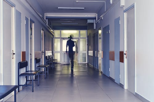 Un couloir de clinique avec une infirmière parcourant le couloir.