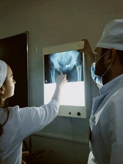 Photo montrant des professionnels de santé examinant une radiographie du bassin pour un diagnostic de la pubalgie par imagerie.