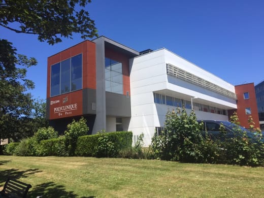 Exterior view of an ELSAN clinic building with a green garden in front.