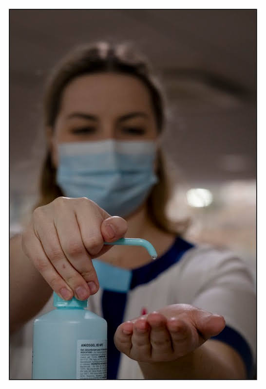 Infirmière qui respecte le protocole sanitaire: se met du gel hydroalcoolique