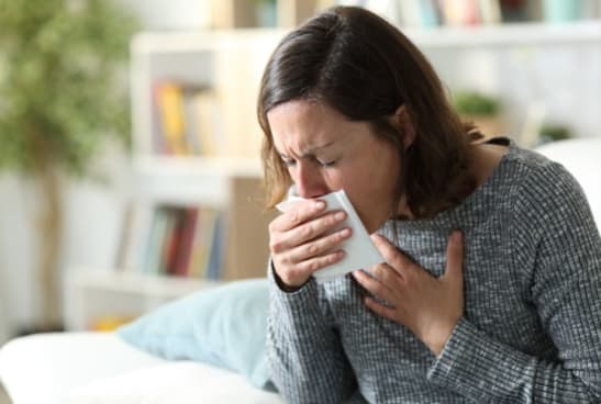 La pneumopathie chez l'adulte. Femme toussant dans un mouchoir.