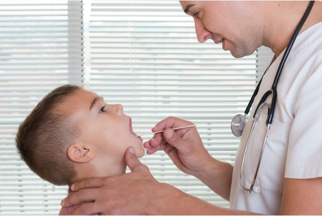 Angine rouge : un médecin examine la gorge d'un jeune garçon.