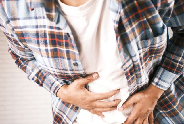 Dyspepsie : un homme se tient le ventre de douleur.