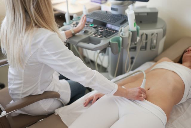 Echographie 2ème trimestre : image d'un médecin radiologue réalisant une échographie d'une femme enceinte.