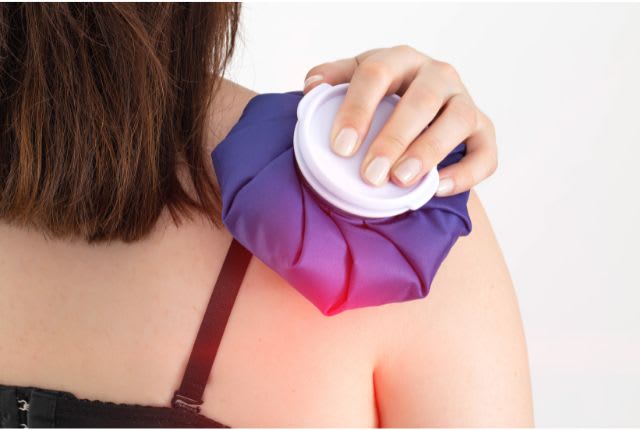 Myalgie : définition, causes, traitements. Une femme applique une petite bouillotte sur épaule.