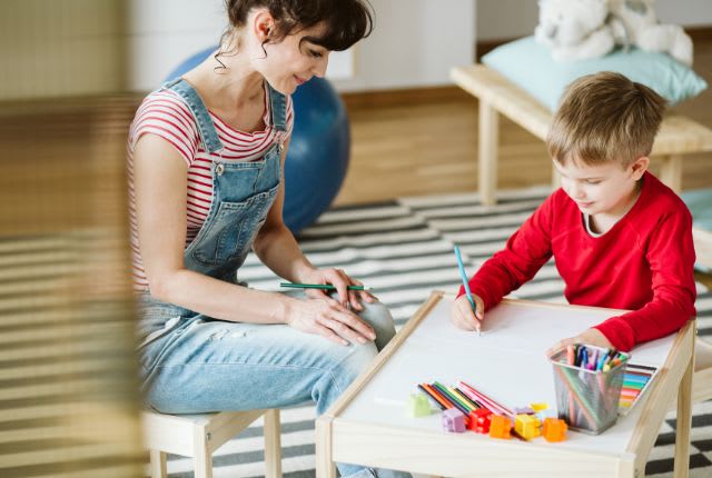 TDAH ou trouble du déficit de l'attention : une maman avec son enfant en train d'écrire sur une petite table.