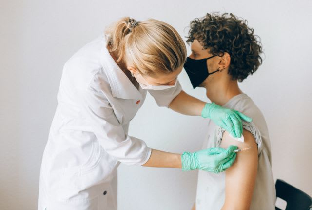 Cas de rougeole : cluster en Isère 2025. Image d'un jeune homme masqué en train de se faire vacciner par une soignante elle-même masquée.