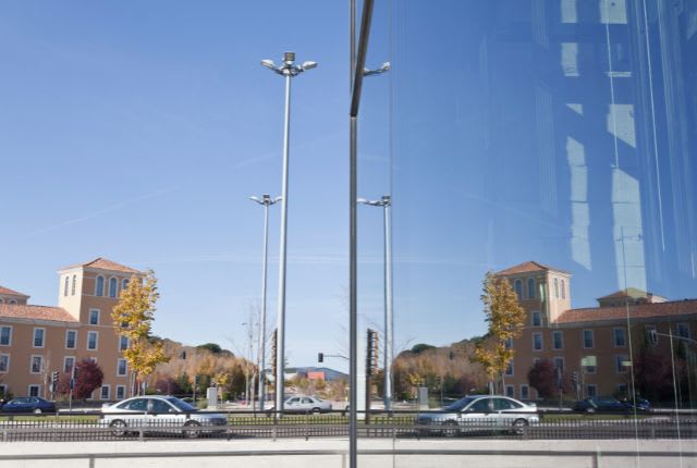 Diplopie : vision double. Un immeuble et une voiture se dédoublent dans un miroir.