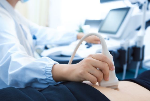 Réalisation d'un examen d'échographie. Un soignant passe une sonde sur le ventre d'un patient.