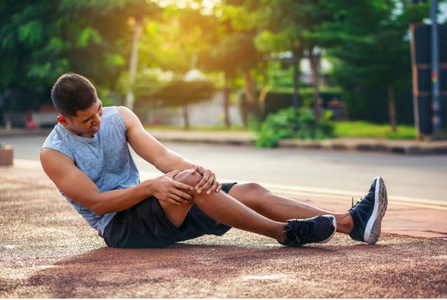 Un sportif par terre se tient le genou. Le syndrome rotulien est un trouble du genou causant une douleur intense autour de la rotule.