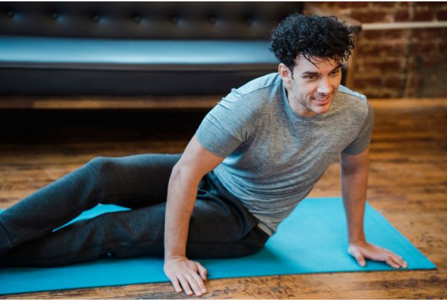 Homme sur un tapis de gym en train de réaliser une torsion pour illustrer de façon symbolique une torsion testiculaire.