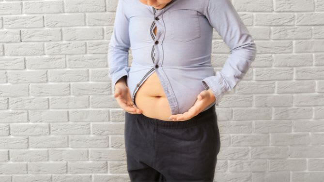 Journée nationale de dépistage de l'obésité infantile. Un jeune garçon n'arrive plus à boutonner sa chemise sur son ventre un peu proéminent.