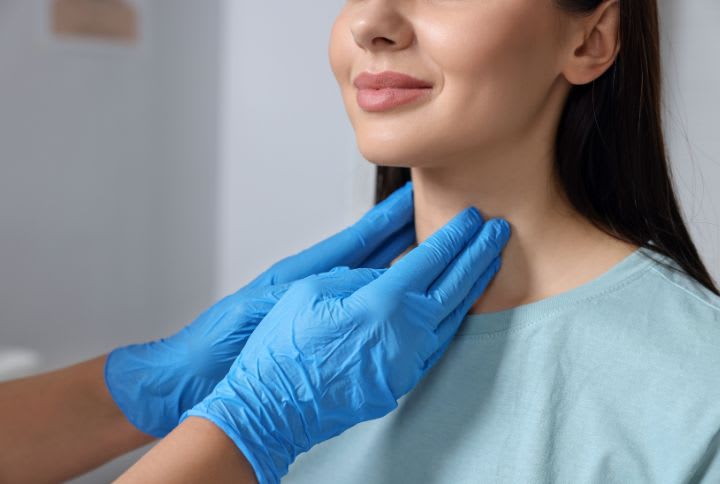 Cancer de la thyroïde : image d'une femme étant auscultée au niveau de la thyroïde par un médecin