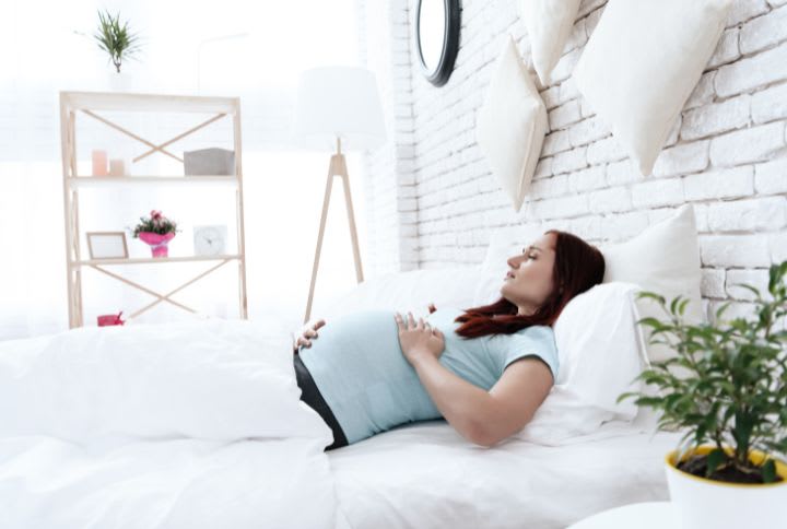 Maux de ventre en période de grossesse : image d'une femme enceinte alitée souffrant de maux de ventre