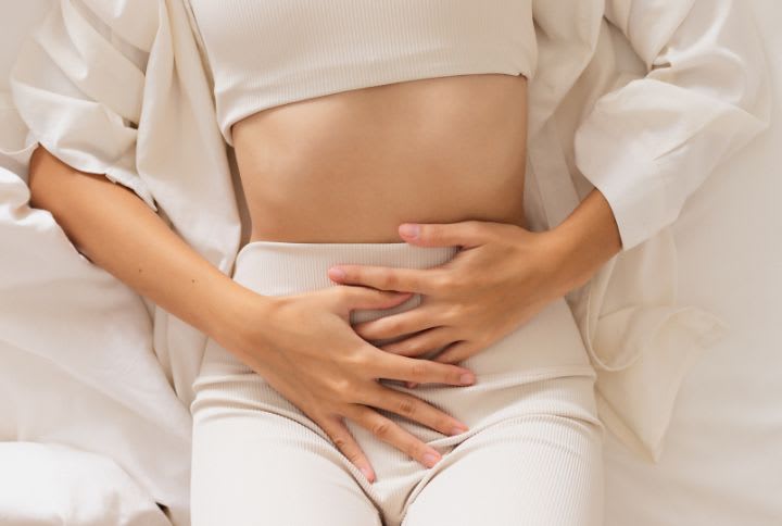 Perte blanche : photo d'une femme allongée sur un lit se tenant le bas ventre