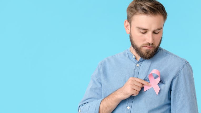 Homme chemise bleu tenant à la main le symbole du cancer du sein 