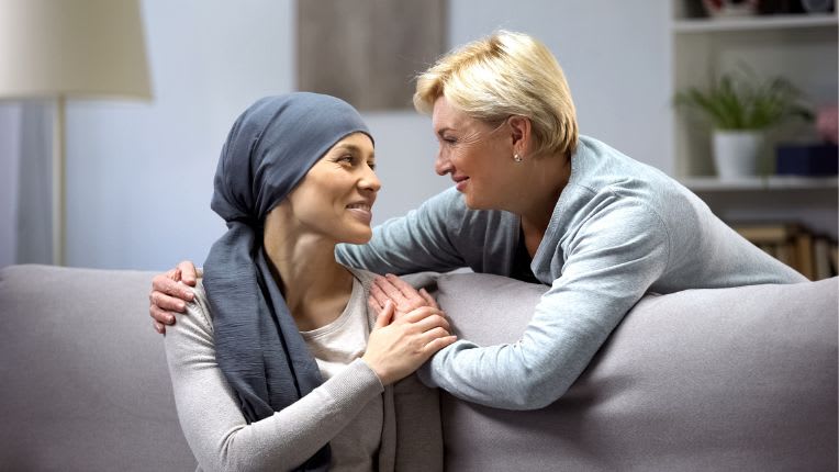 Remission de cancer : image d'une femme malade du cancer ayant appris sa remission. Une amie lui tient l'epaule et l'encourage.