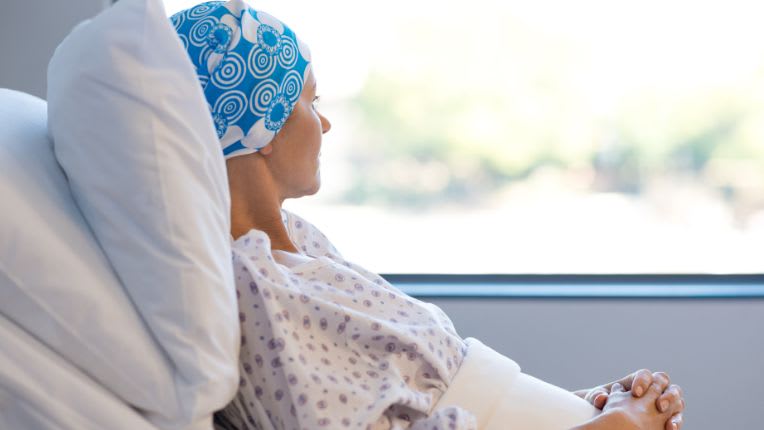 Cancer généralisé : une femme avec un foulard sur la tête alitée dans une chambre d'hôpital.