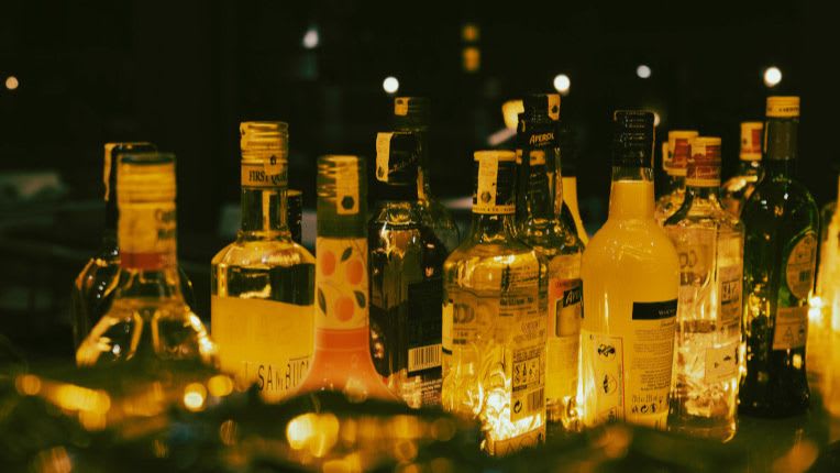 Est-ce que l'alcool peut provoquer un cancer du pancréas ? Image d'une table de bar où figurent plusieurs bouteilles d'alcool la nuit. Licence Creatives Commons pexels-holoshuriken.