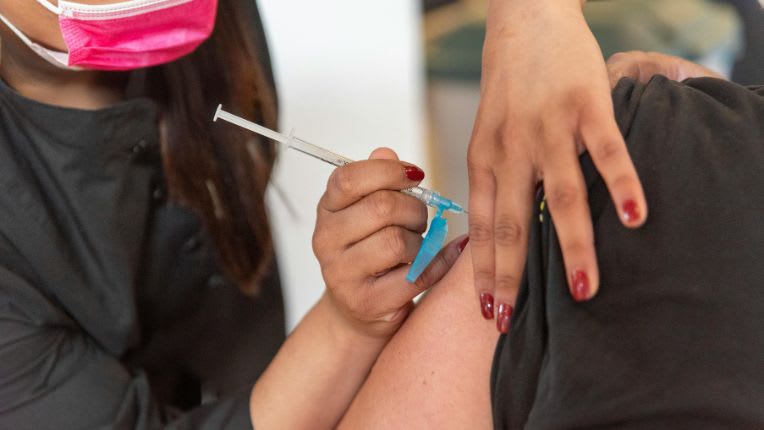 Vaccin contre le chikungunya Ă Toulouse Compans. Une soignante avec un masque rose plante son aiguille dans le bras d'une patiente.