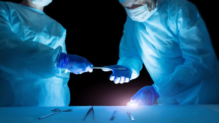 Deux chirurgiens retirent l'adénome de la prostate d'un patient en utilisant un laser.