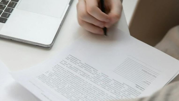 Deuxième avis médical. Patients internationaux ELSAN. Image de la main d'une personne en train d'écrire sur un document devant son ordinateur.