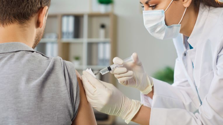 Fièvre jaune : image d'une soignante masquée en train de vacciner un homme de dos.