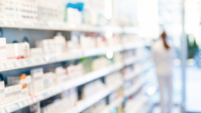 Fièvre jaune traitements : image floutée d'une étagère de médicaments dans une pharmacie.