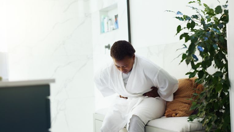 Journée mondiale de l'endométriose. Image d'une jeune femme assise se tient le ventre de douleur.