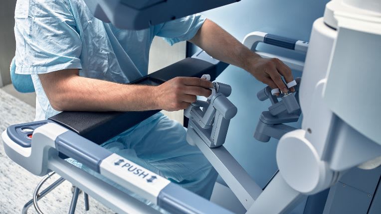 Opération du côlon par robot à  Montauban. Image d'un chirurgien manipulant un robot.