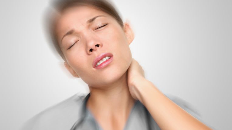 Torticolis. Image d'une femme qui se tient le cou et grimace de douleur.