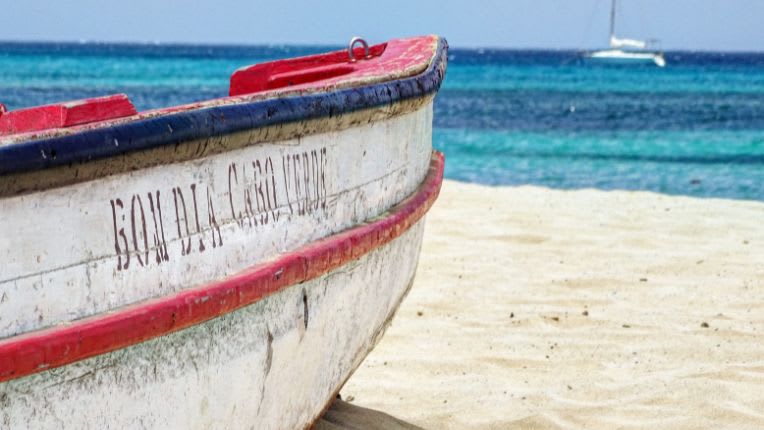 Vaccin Cap vert; Image d'une barque typique sur la plage devant la mer bleue.