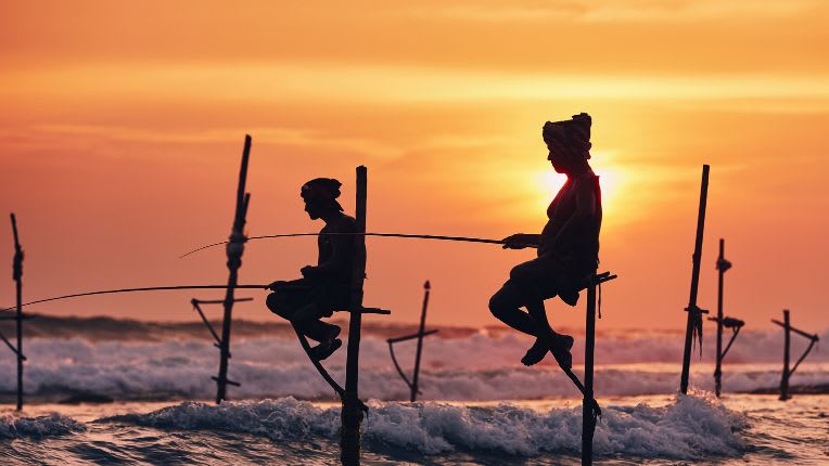 Vaccin Sri-Lanka. Pêcheurs traditionnels positionnés sur des perches au-dessus de la mer.