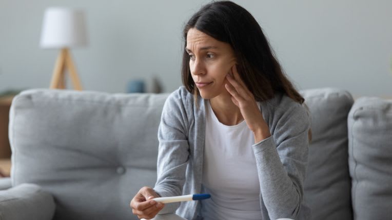Infertilité. Une femme a l'air dépité avec un test de grossesse dans la main.