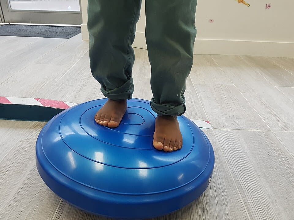 Image des pieds d'un enfant de 2 ans juché sur une plateforme. Atteint de pied bot bilatéral, ses pieds ont une apparence normale en cours de traitement fonctionnel. Image creative commons.